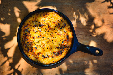 Delicious Argentinian Provolone Yarn Cheese (Provoleta) that was cooked in a cast iron skillet over the embers presented on an old wooden board