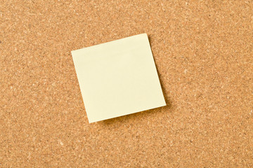 Empty yellow sticky paper memo note on cork board