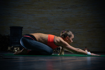 Slim sporty lady bending her back and putting hands on the floor