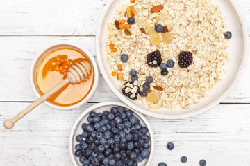 Oatmeal with fruit and honey on a white wooden table. Healthy food. Top view.
