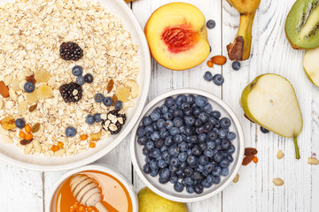 Oatmeal with fruit and honey on a white wooden table. Healthy food. Top view.