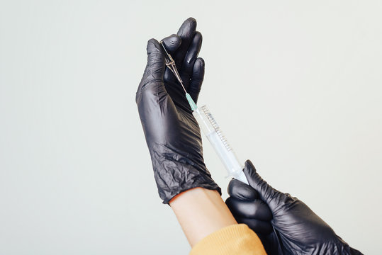 Of man hands with black gloves holding a syringe and vial of medicine. Preparation for injection, on a white background.