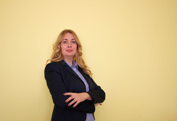 Business young blond woman in a blue shirt and jacket on a yellow background.  Copy space for text.