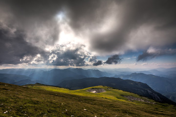 View from Rax plateau, full of fresh, green grassy meadow with blue dramatic cloudy sky to valley and alpine  hills, Raxalpe, Schneeberg massif, Alps, Lower Austria