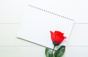 Present gift with red rose flower and notebook on wooden table, 14 February of love day with romantic, copy space with note or diary writing text for you, valentine holiday concept, top view.
