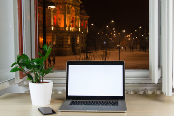 Laptop on the desk in front of the open window at night