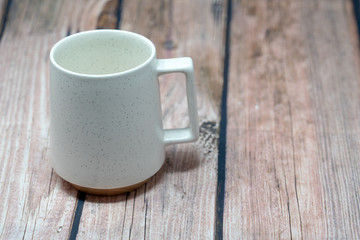 Ceramic white coffee cup isolated on a dark wooden background. Cup is empty