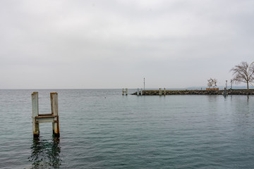 Outdoor scenery of riverside, embankment and pier at Geneva Lake without people with background of overcast cloudy sky in Lausanne, Switzerland.