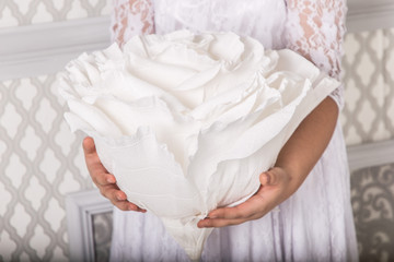 Fototapeta na wymiar Young beautiful woman in a white dress posing with a big white paper flower