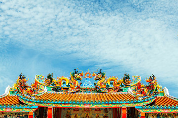 Dragon statue, decorated on the roof of a Buddhist temple in Thailand. Blue sky background with light clouds