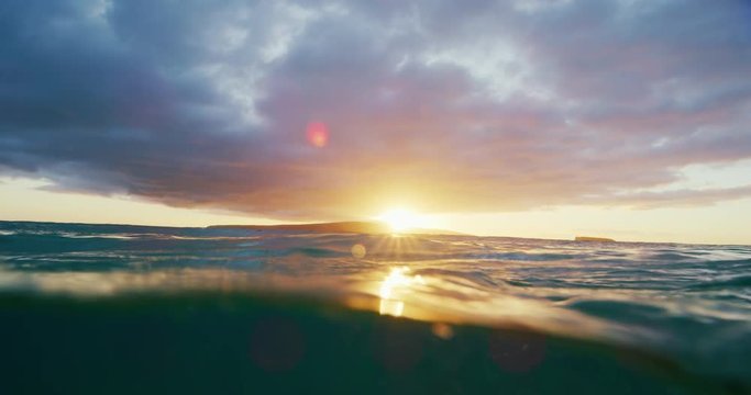 Beautiful golden sunset into the ocean, over under split view from in the water, abstract nature landscape