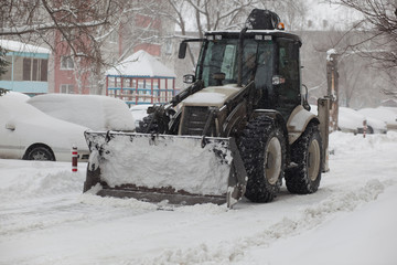 the tractor cleans the snow in the city