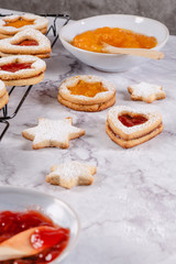 Heart shaped linzer cookies with strawberry and pumpkin jam sprinkled with powdered sugar