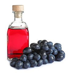 Bottle with wine vinegar and fresh grapes on white background