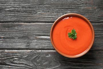 Bowl with fresh homemade tomato soup and space for text on wooden background, top view
