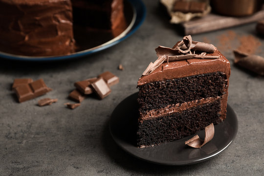 Naklejki Plate with slice of tasty homemade chocolate cake on grey table. Space for text