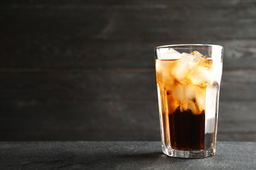 Glass of refreshing cola with ice cubes on table. Space for text