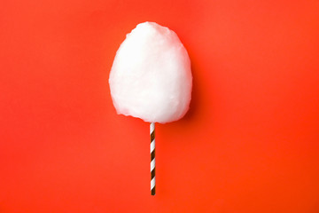 Straw with yummy cotton candy on color background, top view