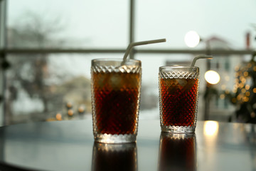 Glasses of cold cola on table against blurred background