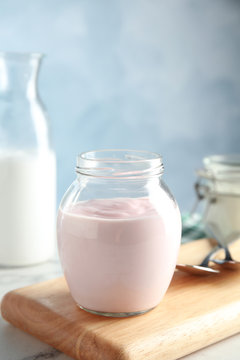 Glass jar of fresh yogurt on table. Space for text
