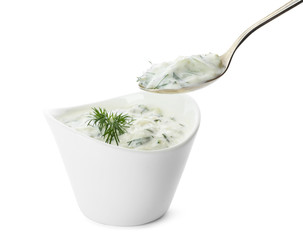 Spoon and bowl of cucumber sauce on white background. Traditional Tzatziki © New Africa