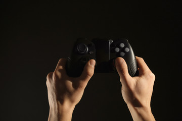 Man holding video game controller on black background, closeup