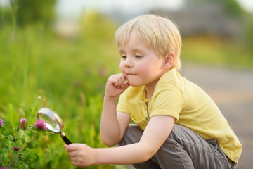 Charming kid exploring nature with magnifying glass