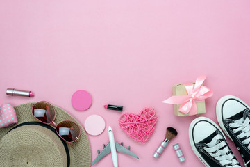 Table top view aerial image of decorations valentine's day & fashion woman background concept.Flat lay items plane to travel.Heart & gift box on pink paper with clothing women & cosmetic for traveler.