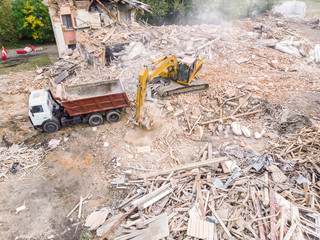 demolition of an old building. hydraulic excavator and dump truck clearing out debris and garbage