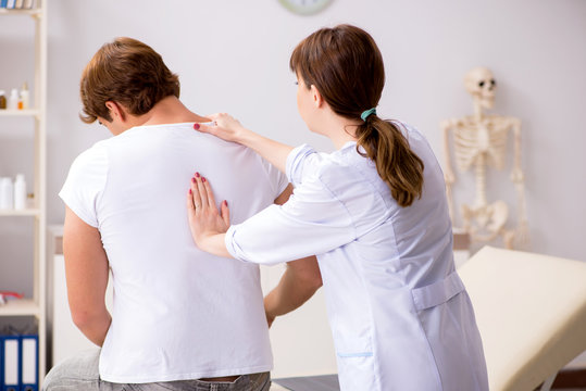 Male patient visiting young female doctor chiropractor 