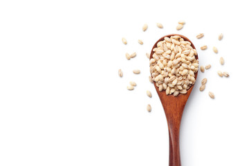 Peeled barley in a wooden spoon, isolated on white background. Top view.