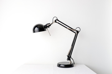 Retro black black desk lamp on white table top on white wall background with copy space product mock up placement 
