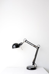 Retro black black desk lamp on white table top on white wall background with copy space product mock up placement 