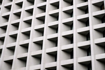 Gray concrete wall with many equal square windows. Abstract city architecture background.