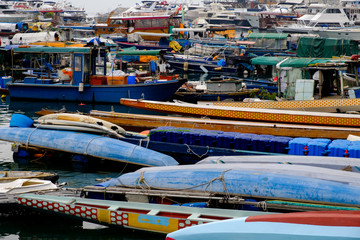 Fototapeta na wymiar A lot of different and multicolored fisher’s boats and small vessels on the water near the pear. Abstract seaport background.
