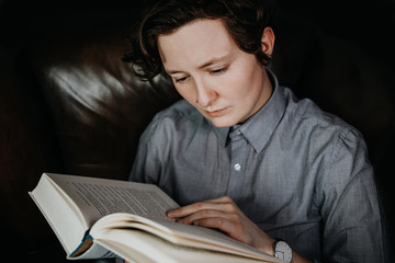 Fototapeta na wymiar Junger Mensch liest interessiert in einem Buch 
