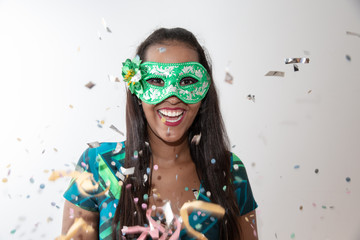 people, holidays, emotion and carnival concept - happy young woman with mask and confetti at...