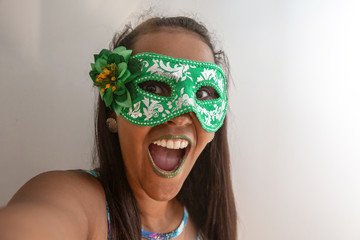 people, holidays, emotion and carnival concept - happy young woman with mask and confetti at carnaval party. Carnaval concept