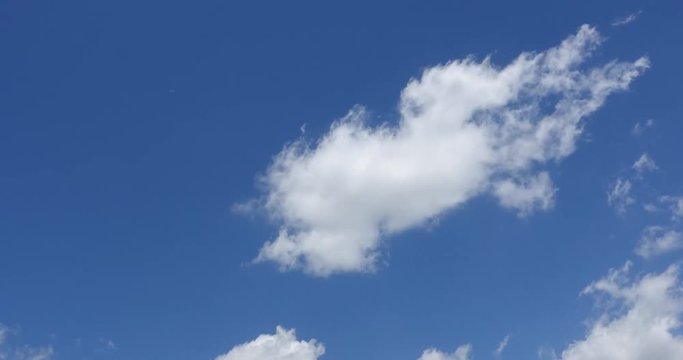 Beautiful bright blue sky with white fluffy clouds on a clear sunny day. Royalty high-quality free stock timelapse footage of blue sky with white cloud. Time lapse of natural cloudscape background