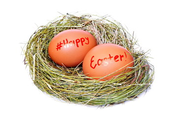 Obraz premium Two brown chicken eggs in straw nest with red color text happy Easter and sign hashtag for social network on white background. Isolated