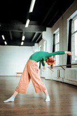 Good-looking slim yoga coach in a green turtleneck doing arching