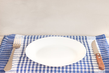 Empty plate on tablecloth or napkin on wooden table over cement background