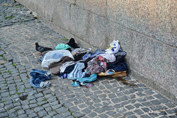 dirty clothes and garbage thrown on the city sidewalk near the wall