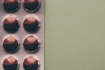 Blister with brown tablets on a green background.