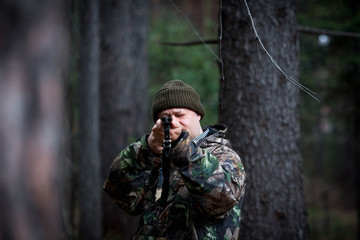 hunter with a gun in the forest cures prey