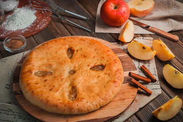 Homemade apple pie on a wooden kitchen table with ingredients. Traditional baking header. Delivery...