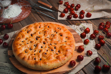 Homemade cherry pie on a wooden kitchen table with ingredients. Traditional baking header. Delivery menu with copy space