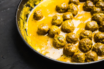 Meatballs in creamy sauce in a frying pan. Selective focus. Shallow depth of field. 