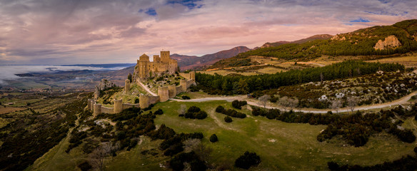 Aerial panorama view of medieval Romanesque partially restored Loarre castle near Huesca in Aragon province Spain surrounded by  fog and clouds - obrazy, fototapety, plakaty