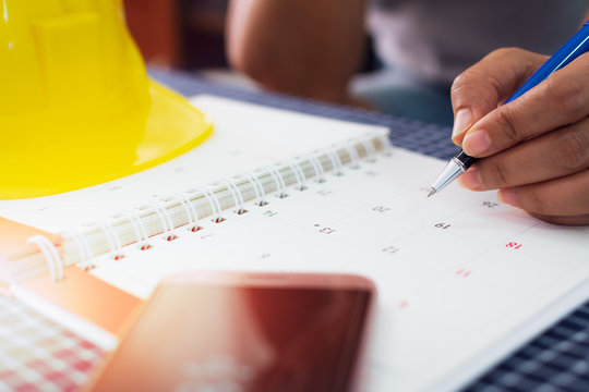 Hands of female architect is planning and managing work on the calendar.